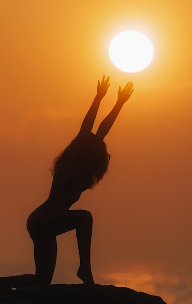 Foto silueta de mujer en asana de yoga con concepto de religión y espiritualidad del disco solar