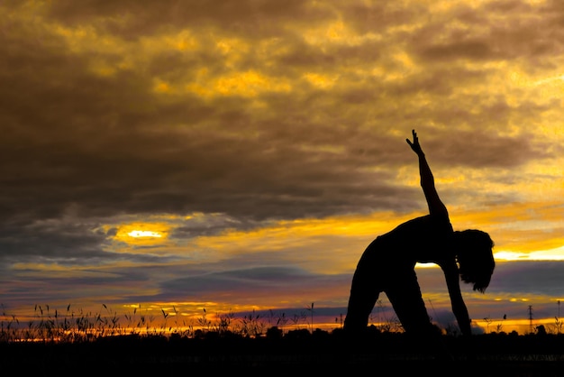 silueta, de, mujer asiática, juego, yoga, en, ocaso