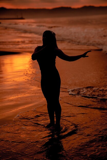 Silueta de una mujer asiática jugando en el agua en la playa con fuertes olas rompiendo