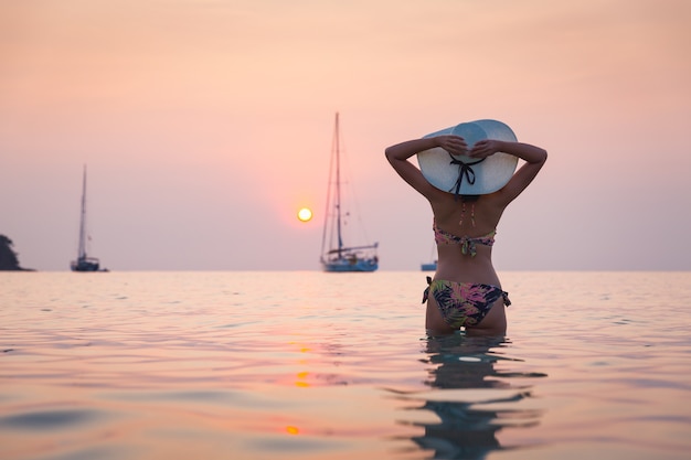 Silueta de mujer asiática viajero con bikini relajante en la playa al atardecer en Koh Kood, Tailandia