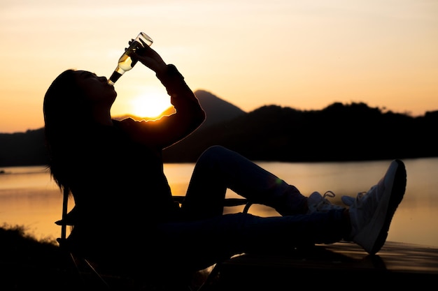 Silueta mujer bebiendo agua en la playa al atardecer