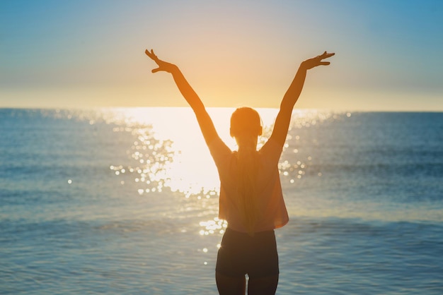 Una silueta de la mujer contra la puesta de sol en el océano o el mar