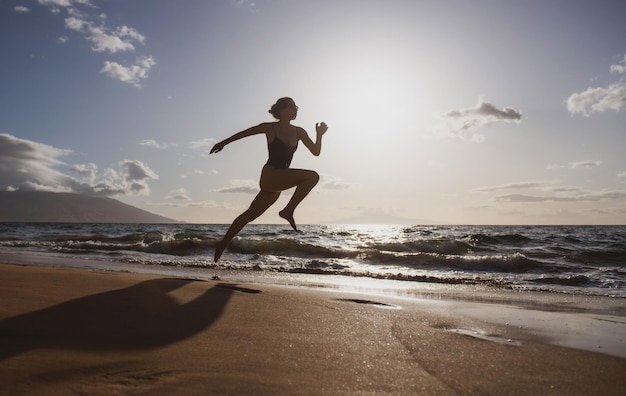 Silueta de mujer corredora haciendo ejercicio en correr sprint entrenamiento en la playa trotar saludable al aire libre ac