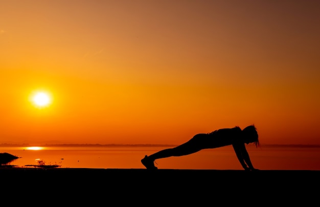 Silueta de mujer deportiva con puesta de sol. Actividad saludable y ejercicio. Estilo de vida y recreación.