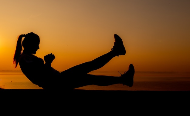 Silueta de mujer deportiva con puesta de sol. Actividad saludable y ejercicio. Estilo de vida y recreación.