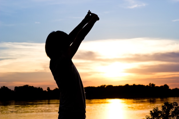 Foto silueta de mujer ejerciendo sobre fondo hermoso atardecer.