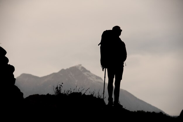 Silueta de mujer excursionista de pie en la cima de la montaña