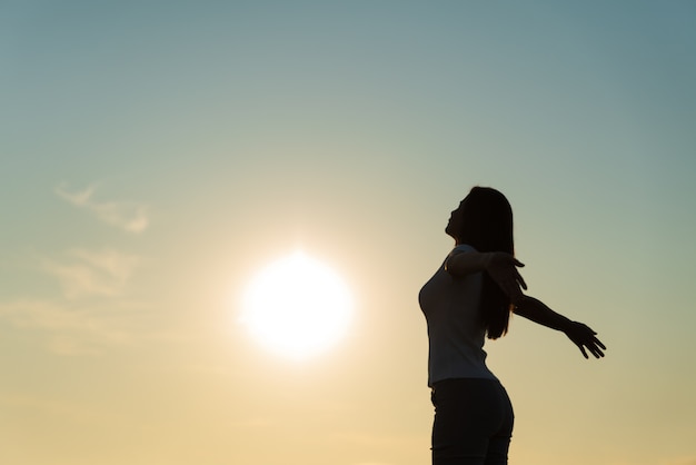 Silueta de mujer extendiendo los brazos, las emociones de libertad.