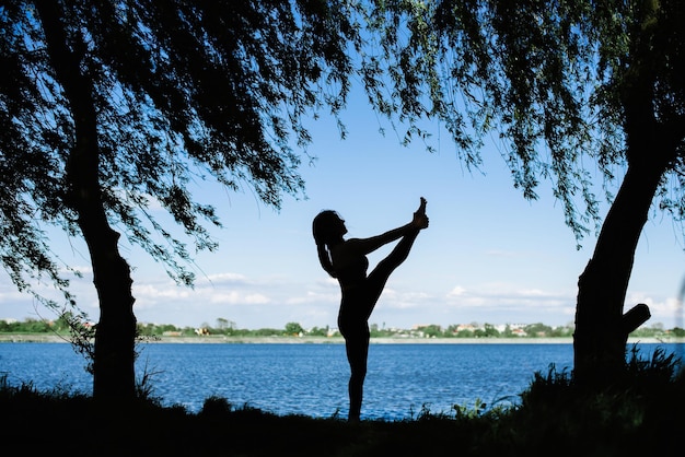 Foto silueta de mujer haciendo yoga al aire libre en el fondo del lago