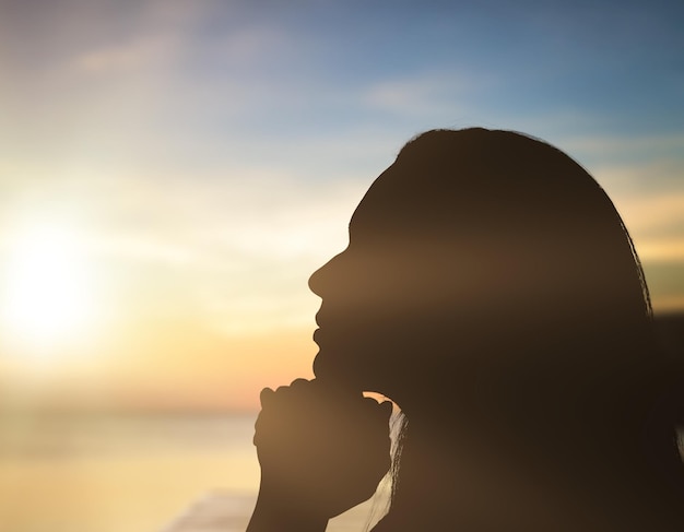 Silueta de mujer joven en la costa del mar al atardecer