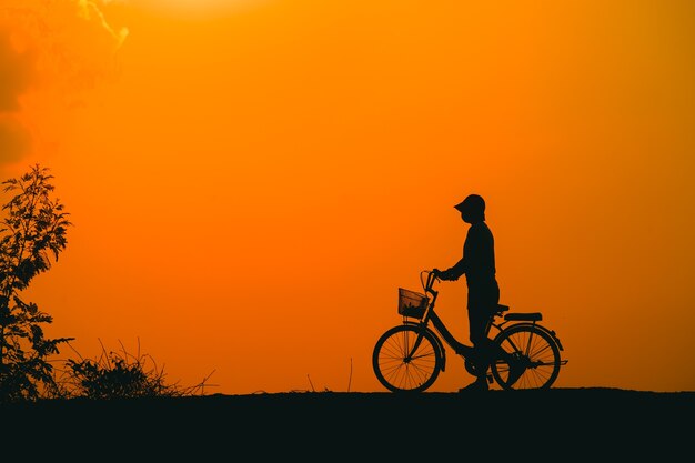 Silueta de una mujer joven de pie tristemente mirando al cielo al atardecer