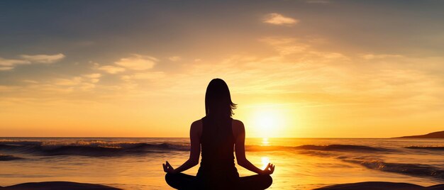 Silueta de una mujer joven practicando yoga en la playa al atardecer