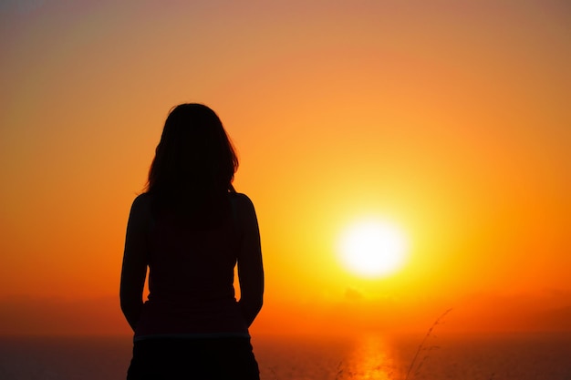 Silueta de mujer junto a la orilla al atardecer