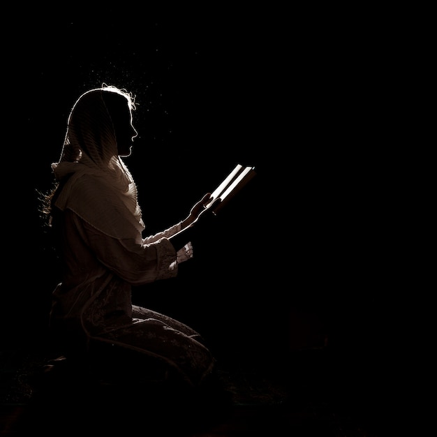 Foto silueta de mujer leyendo en corán