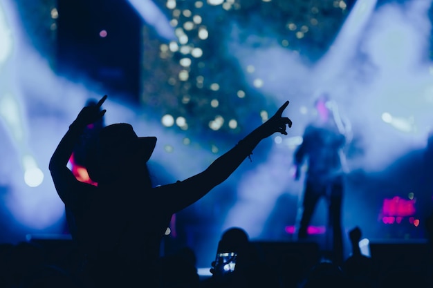 Silueta de una mujer con las manos levantadas en un concierto