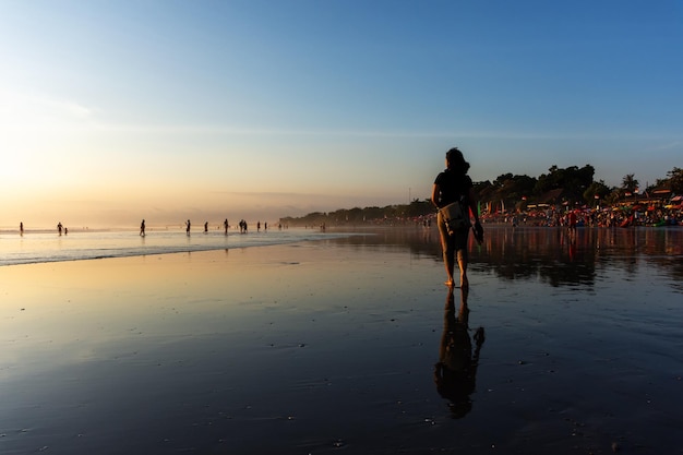 Silueta de mujer paseando y disfrutando del atardecer en la playa de Seminyak en Bali