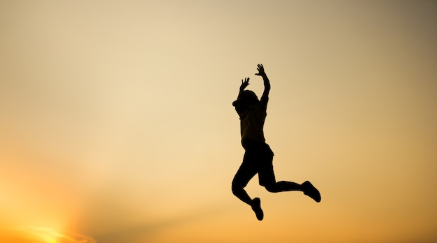 Foto la silueta de una mujer está saltando sobre fondo hermoso de la puesta del sol.