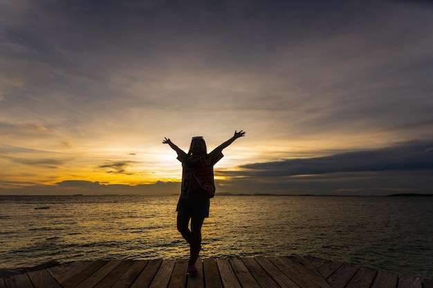 Silueta de mujer saltando sobre el mar al atardecer enfoque suave y clave baja