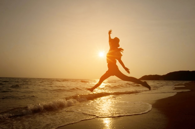 silueta de mujer saltando sobre el mar al atardecer