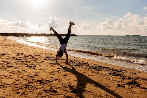 Silueta mujer salto mortal y ejercicio en la puesta de sol en la playa. Deporte y estilo de vida saludable. Nuevo comienzo del día y recreación.
