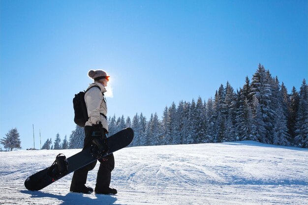 silueta de una mujer con una tabla de nieve en la pista de esquí