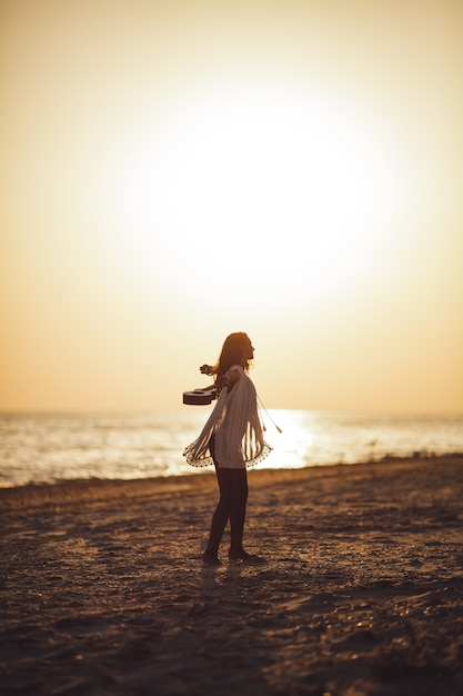 Silueta de la mujer con el ukelele en las vacaciones de verano en la playa