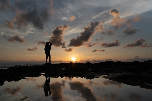 Foto silueta de mujeres con hermoso cielo nublado en la puesta del sol y estanque de reflexión / textura de fondo / cielo natural