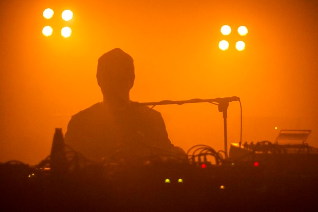 Una silueta de músico electrónico durante un concierto en vivo con luz amarilla Focos de humo de fondo oscuro