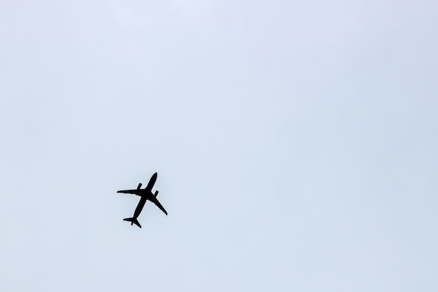 Silueta negra de un avión volando contra un cielo gris azul