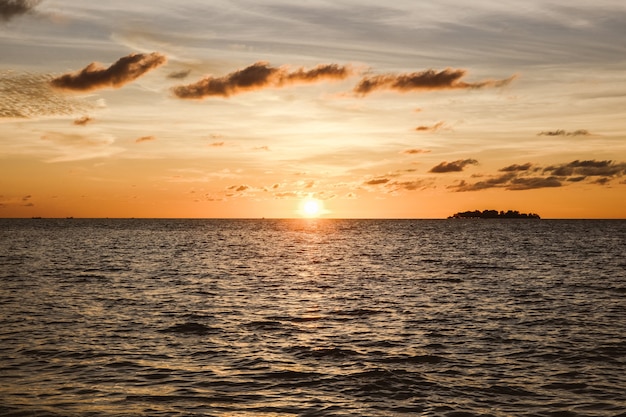 Silueta negra y reflejo del sol en el mar durante la puesta de sol