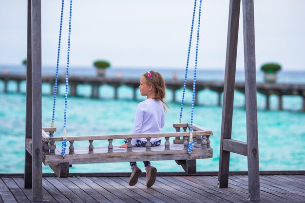 Silueta de niña adorable en columpio al atardecer