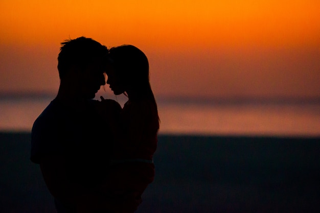 Silueta de niña y papá en la puesta de sol en la playa