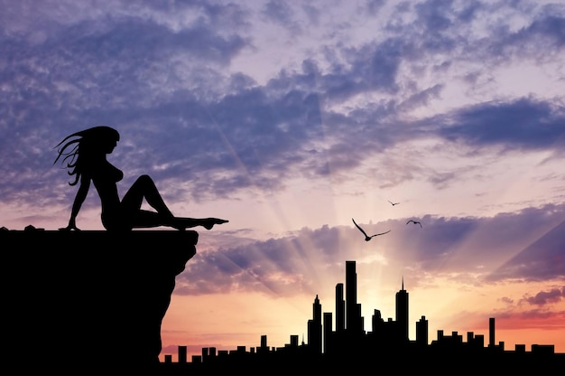 Silueta de una niña sentada mirando el atardecer de la ciudad