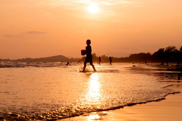 Silueta de niño jugando en la playa al atardecer