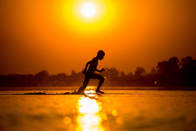 silueta de niños corriendo con diversión en la playa en el río