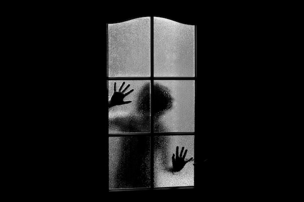 Silueta oscura de niña detrás del vidrio. Bloqueado solo en la habitación detrás de la puerta en Halloween en escala de grises. Pesadilla de niño con extraterrestres, monstruos y fantasmas. Mal en casa en monocromo. Dentro de la casa embrujada.