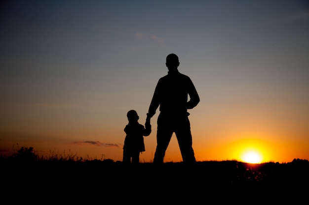 Foto silueta de padre e hijo cogidos de la mano al atardecer