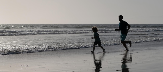 Silueta de padre e hijo corren en el cartel de la pancarta al aire libre de la playa de verano con espacio de copia papá