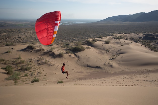 Silueta de parapente volando en la duna