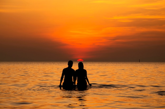 Silueta de pareja caminando hacia el mar con el cielo al atardecer | Foto  Premium