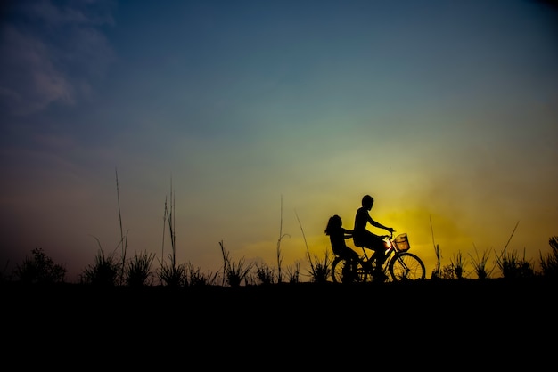 silueta de pareja conduciendo bicicleta tiempo feliz puesta de sol