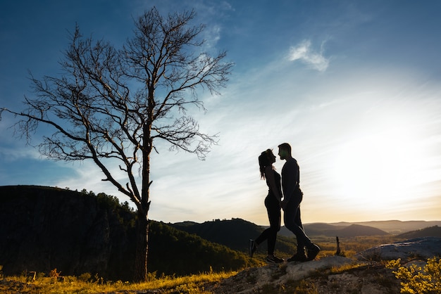 Silueta de una pareja de enamorados. Chico y chica abrazando al atardecer. Pareja viaja. Amantes de la naturaleza. Hombre y mujer mirando la puesta de sol. Amantes al atardecer. Viaja en las montañas. Luna de miel