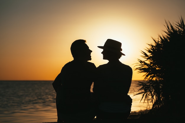 Silueta de una pareja de enamorados a la orilla del mar disfrutando de una puesta de sol
