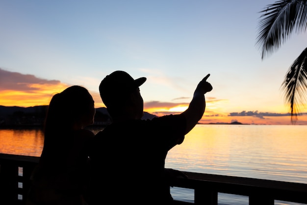 Silueta pareja hombre mano señalando en el cielo al atardecer