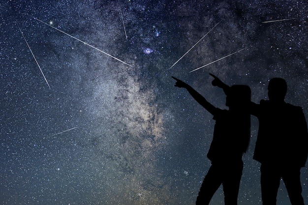 Silueta de pareja joven viendo lluvia de meteoritos. Nigh Sky.