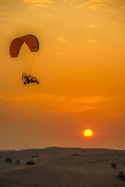 Foto silueta de una persona en parapente contra el cielo durante la puesta de sol