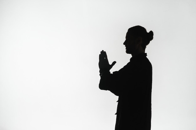 Silueta de una persona practicando ejercicios de energía qigong sobre un fondo claro