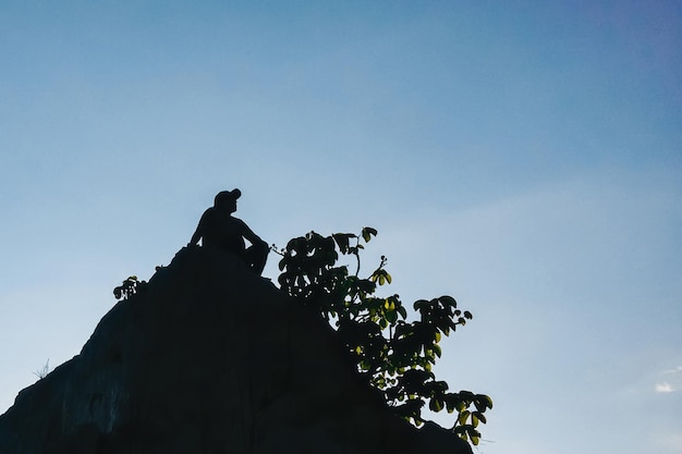 silueta de persona sentada en la cima de una montaña