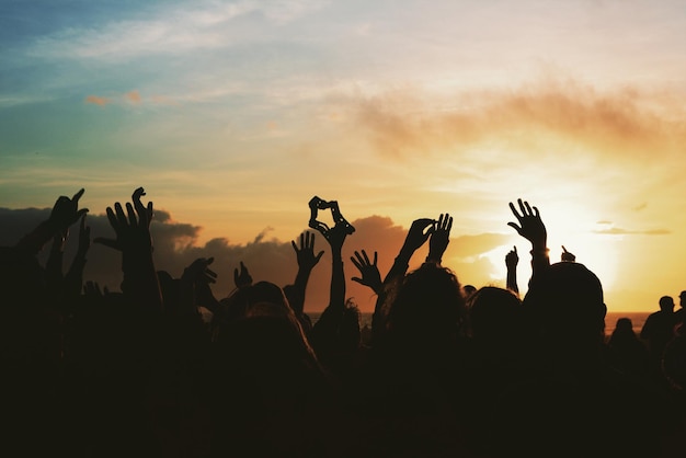 Foto silueta de personas en un concierto de música contra el cielo durante la puesta de sol