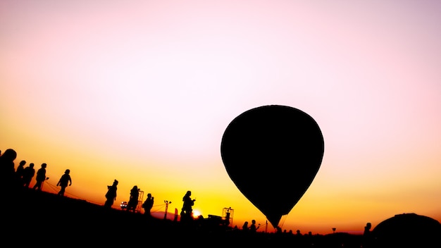 Silueta de personas y globos aerostáticos en el festival de globos.